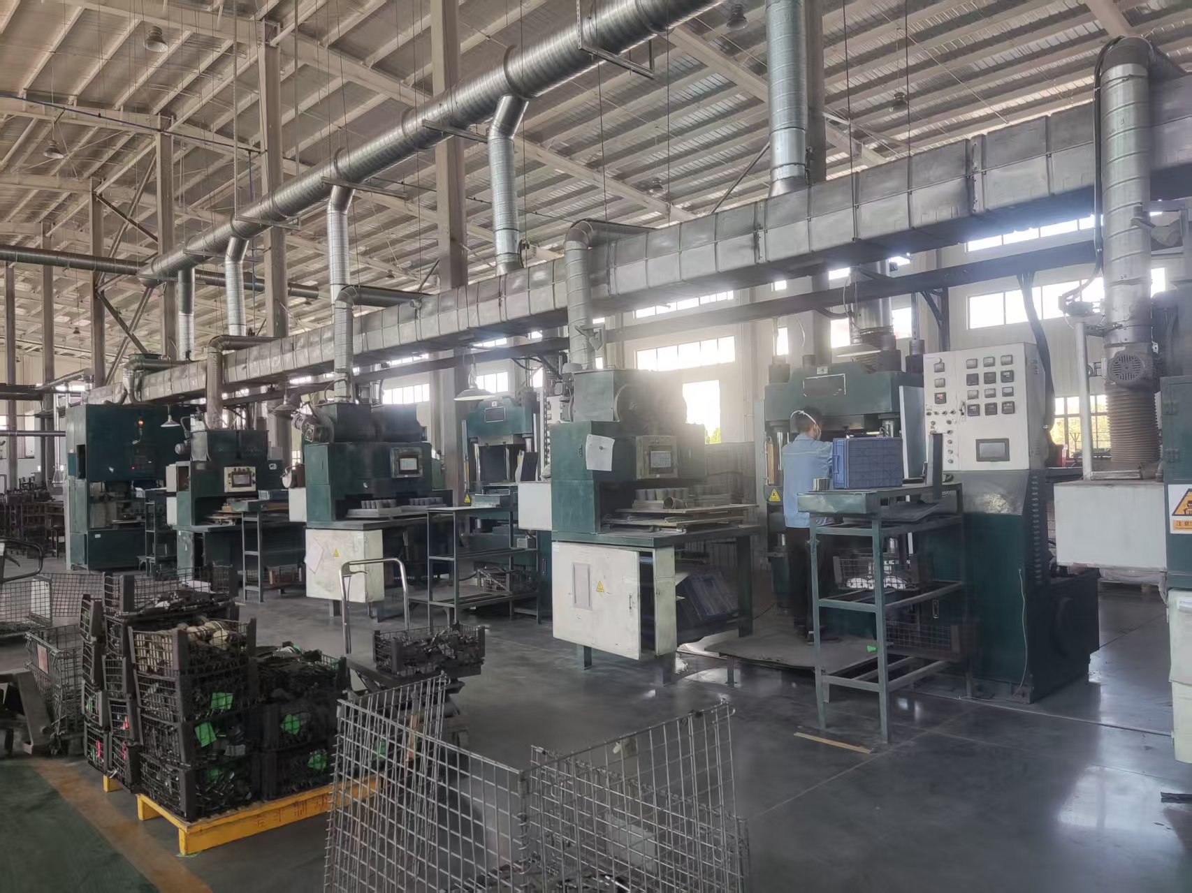 A row of production presses, operator controls and component handling areas.