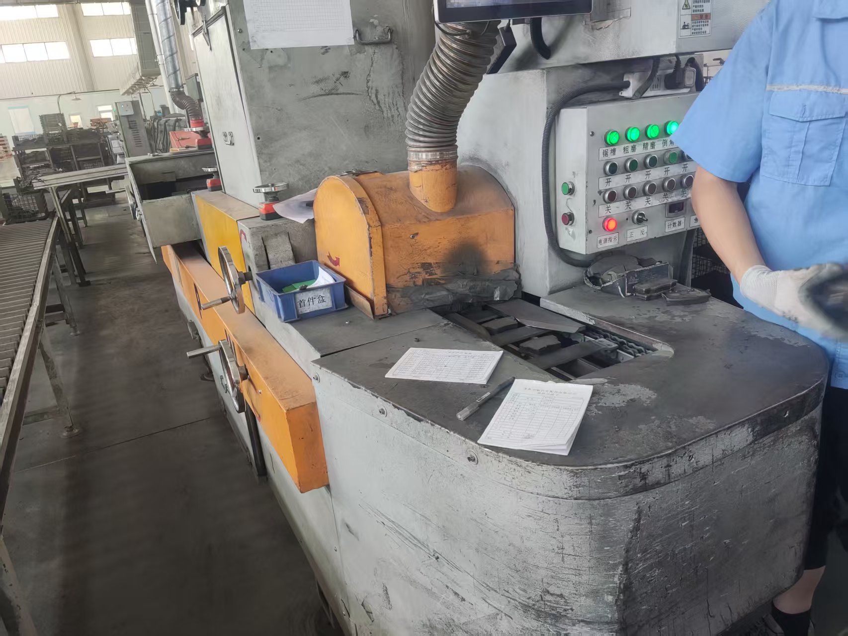 Brake pads moving through a processing workstation with extraction equipment.